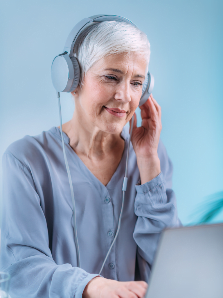 A woman listening to headphones on a a laptop